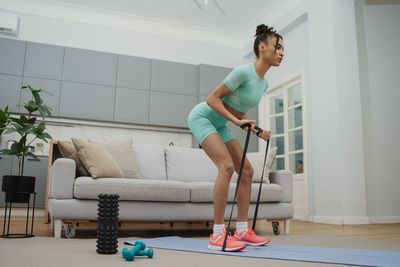 Side view of young woman exercising at home