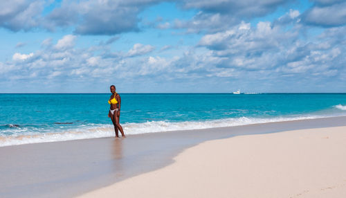 Full length of woman standing at beach against sky