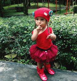 Cute baby girl with finger on lips standing on footpath in park