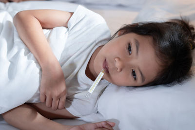 High angle portrait of cute girl lying on bed