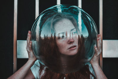 Close-up of thoughtful young woman wearing glass helmet in head against metallic railing