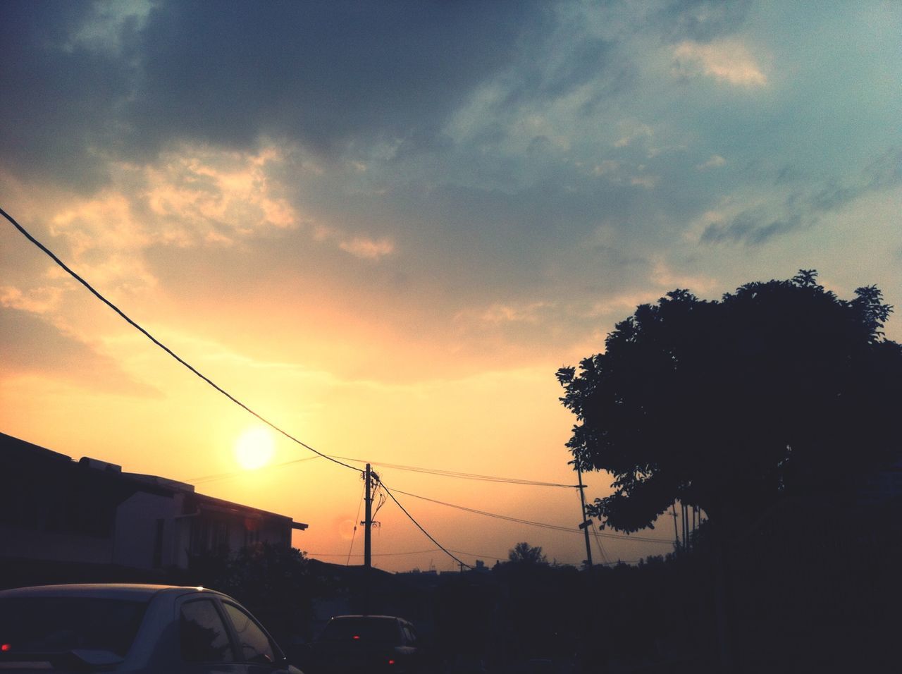 sunset, silhouette, power line, sky, car, electricity pylon, transportation, land vehicle, mode of transport, street light, cloud - sky, cable, low angle view, tree, power supply, electricity, sun, street, orange color, road