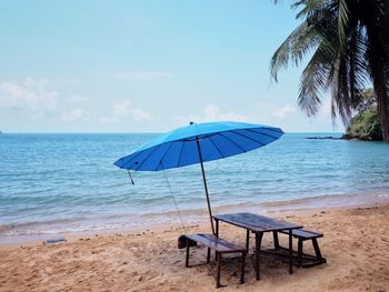 Deck chairs on table by sea against sky