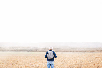 Rear view of man standing on land against sky