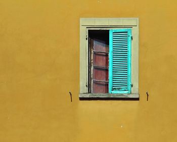 Closed window of yellow wall of house