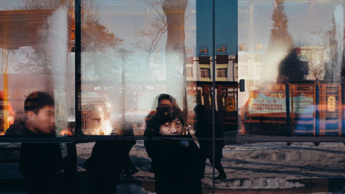 Rear view of people looking through glass window