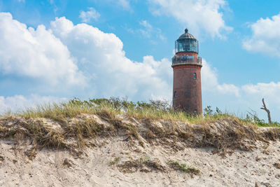 Lighthouse on field against sky