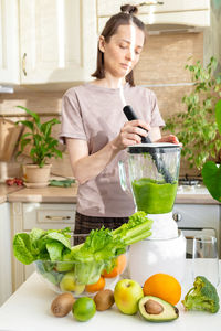 Smiling young woman using mobile phone while standing on table