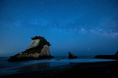 Rock formation in sea against sky at night