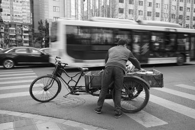 Rear view of man riding motor scooter on street