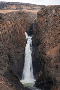 Powerful cascades of litlanesfoss waterfall amidst basalt columns against sky