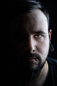 Close-up portrait of young man against black background