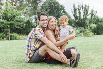 Portrait of family sitting on grass at back yard