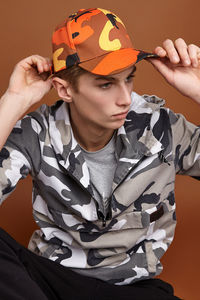 Portrait of boy wearing hat holding while sitting against wall