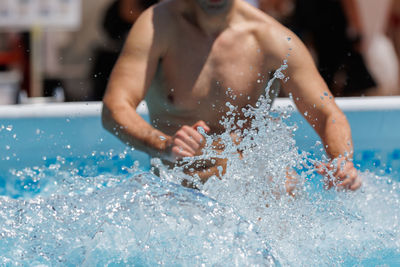 Boy doing water aerobics outdoor in a swimming pool.