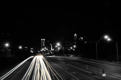 High angle view of light trails over illuminated street against clear sky at night