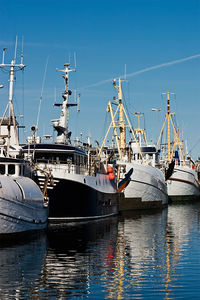 Sailboats moored at harbor against blue sky