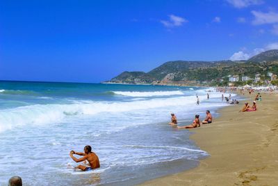 People enjoying on beach against clear sky