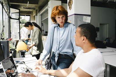 Senior woman talking with repairman sitting at shop