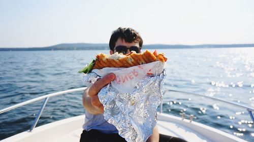 Young man sailing in sea against sky