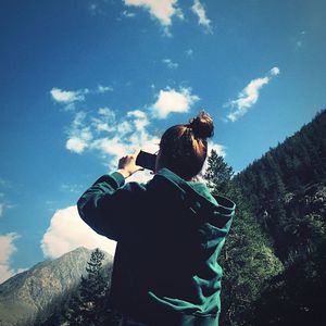 Rear view of woman photographing against sky