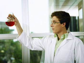 Scientist holding red chemical in laboratory glassware