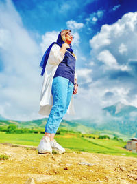 Side view of young woman standing on land against sky