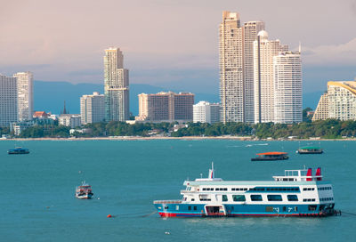 Boats in sea against modern buildings in city