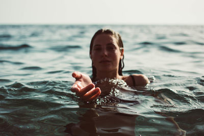 Portrait of woman gesturing while swimming in sea