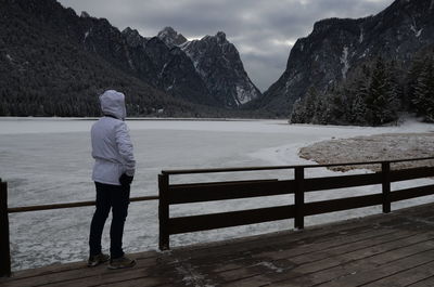 Rear view of woman standing on jetty against lake