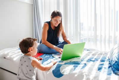 Mother using laptop while kid looking at it