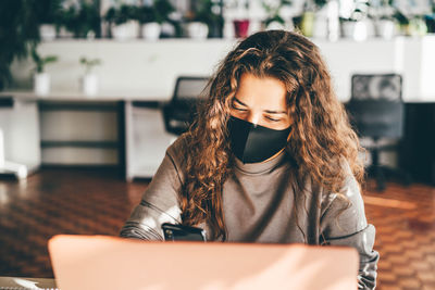 Businesswoman wearing mask using laptop