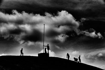 Low angle view of silhouette people standing against sky