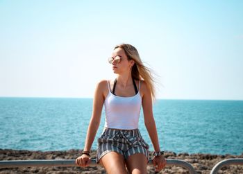 Happy young woman against sea against clear sky