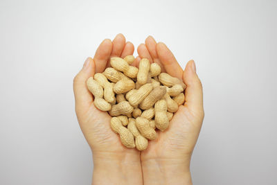 Close-up of hand holding bread against white background