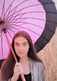 Portrait of beautiful woman holding pink umbrella