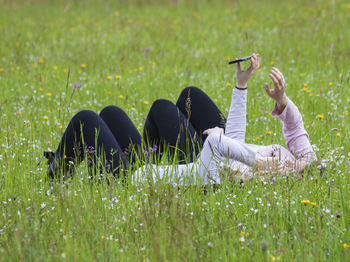 Female friends lying on grass while taking selfie from mobile phone