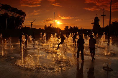People on wet street during sunset