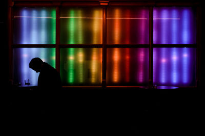 Side view of a silhouette man against illuminated window