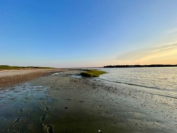 Scenic view of beach against clear sky during sunset