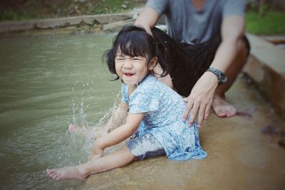 Cute girl with father playing in pond