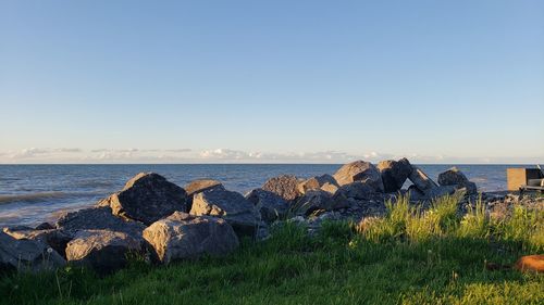 Rocks by sea against clear sky