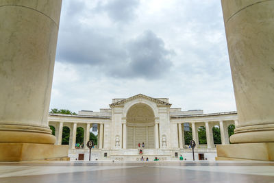 People in front of historical building against cloudy sky