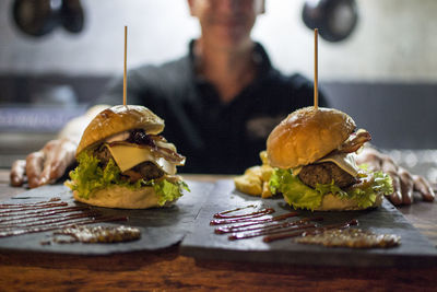 Midsection of mature woman with burgers on table in cafe