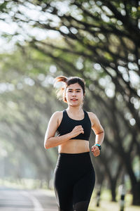 Young woman standing against trees
