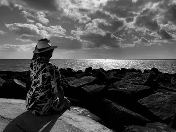 Rear view of people looking at sea shore against sky