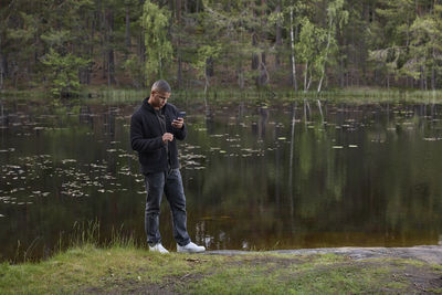 Young man using cell phone at lake