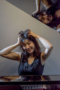 Portrait of smiling woman with hands in hair at home