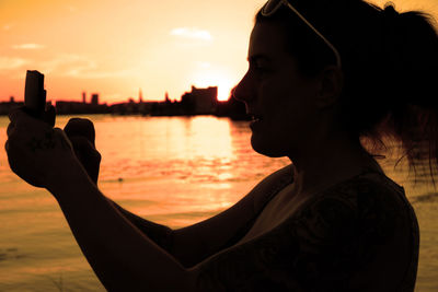 Close-up of silhouette man using mobile phone at beach