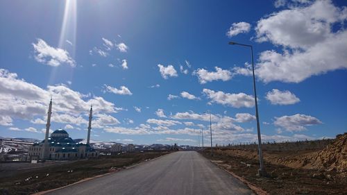 Empty road amidst land against sky